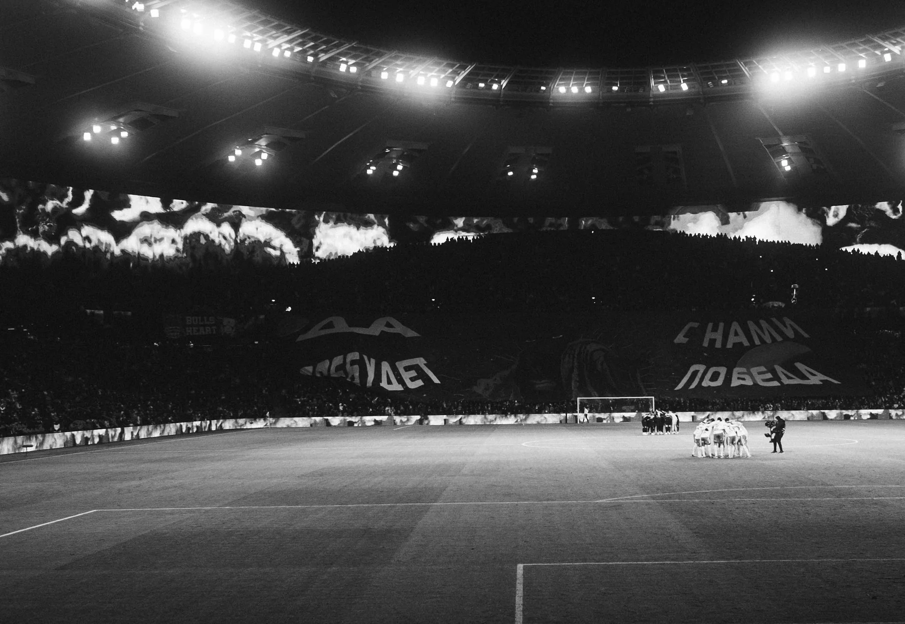Football stadium and supporters under bright night lights